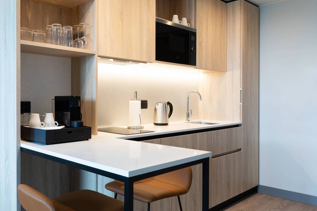 Eine moderne Küche mit weißer Arbeitsplatte, Edelstahlgeräten und Holzschränken.