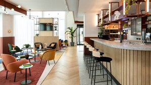 Un área de bar moderna con una barra alargada, taburetes y diversas opciones de asientos, como sillas y mesas.