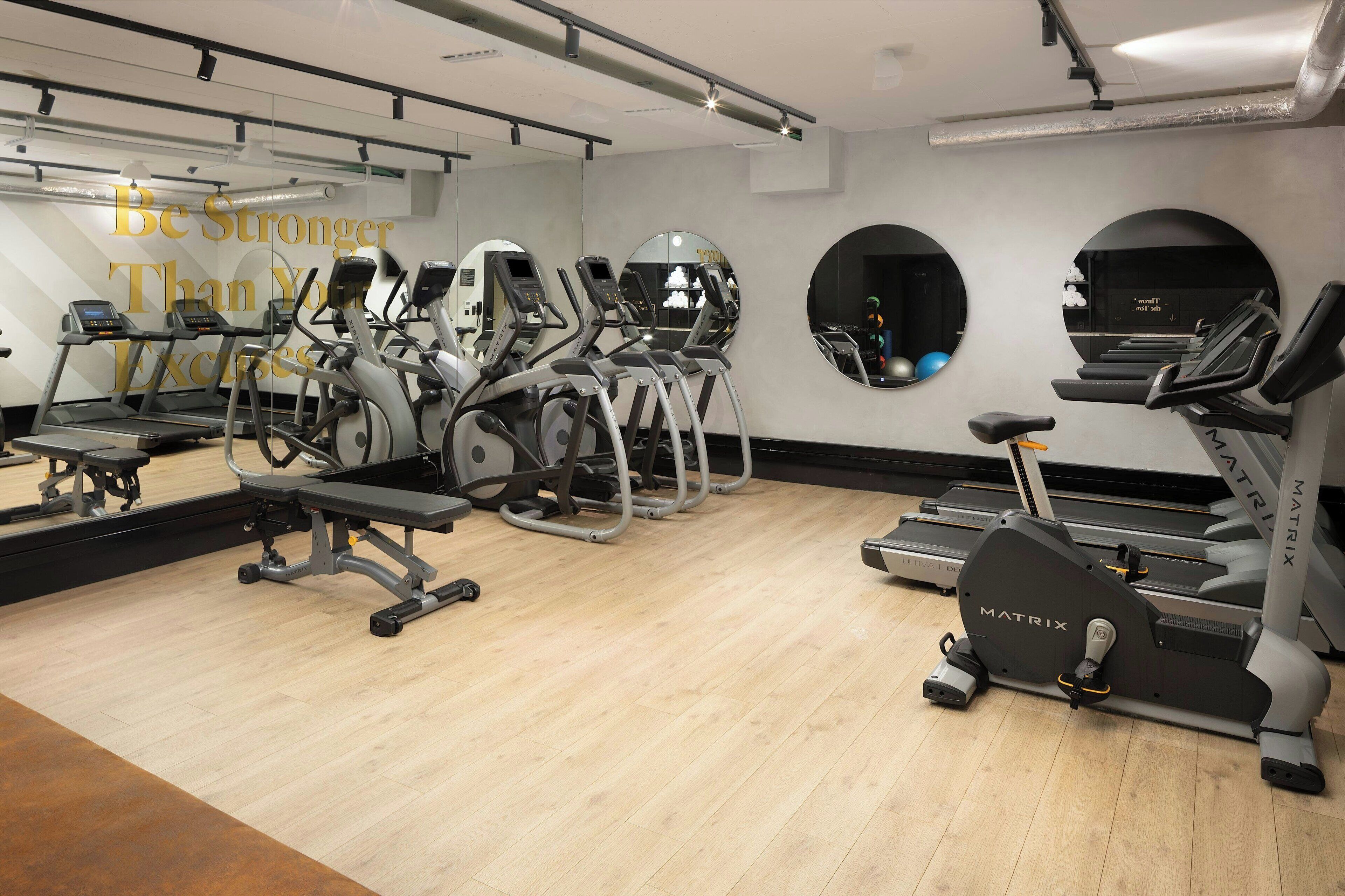 A gym with treadmills, elliptical machines, and a bench.