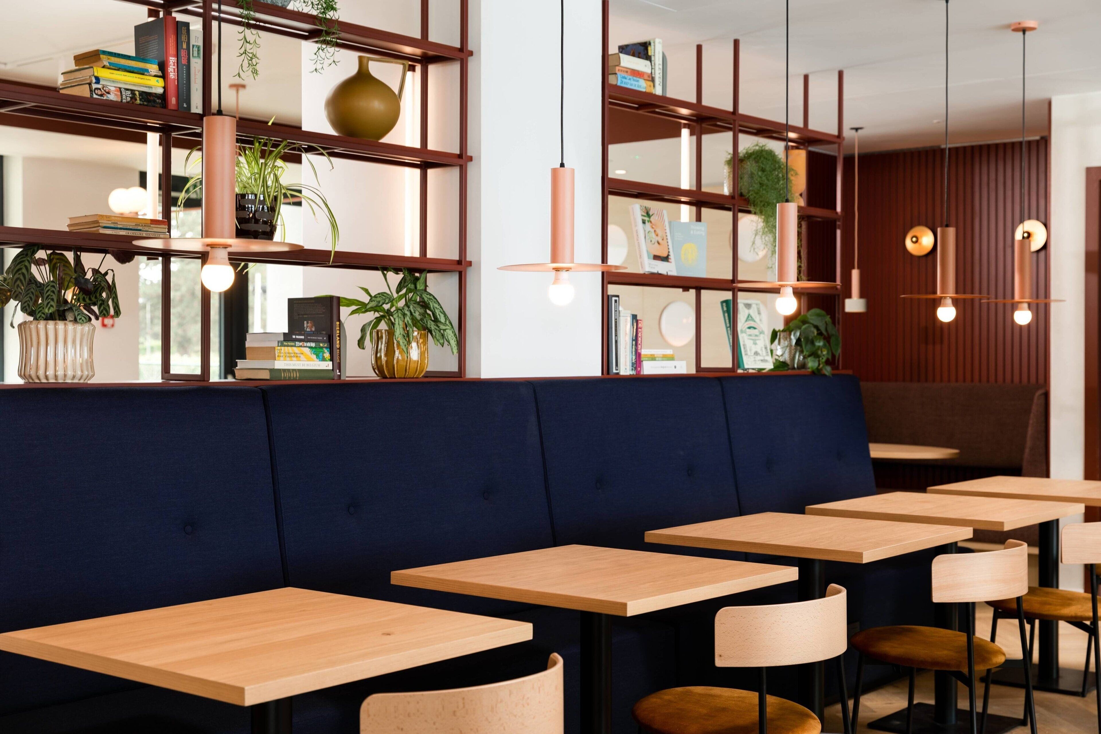 Un interno ristorante moderno con tavoli in legno e sedute imbottite blu.