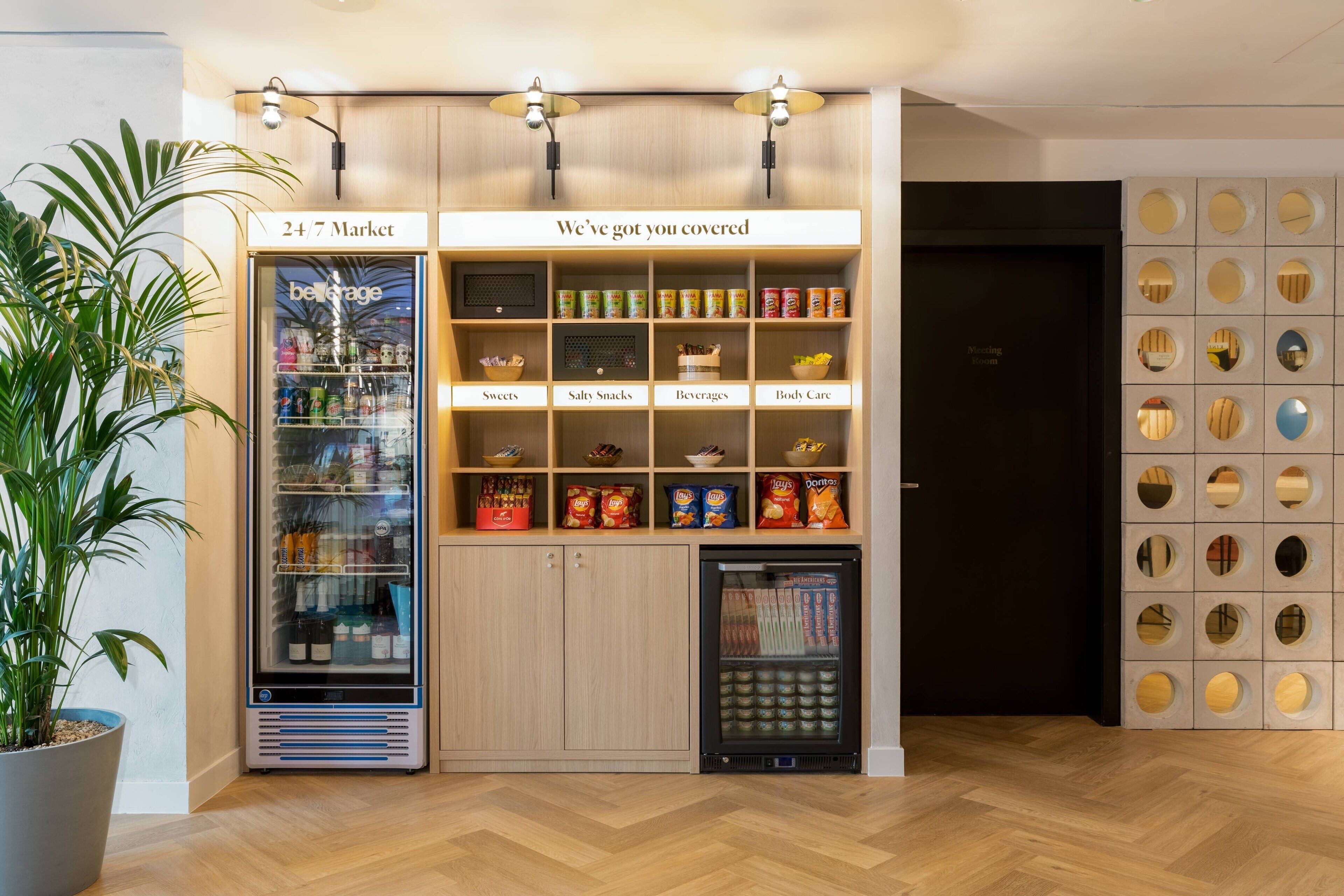 Zona de máquinas expendedoras con tienda disponible las 24 horas, que ofrece dulces, aperitivos salados, bebidas y productos de cuidado personal.