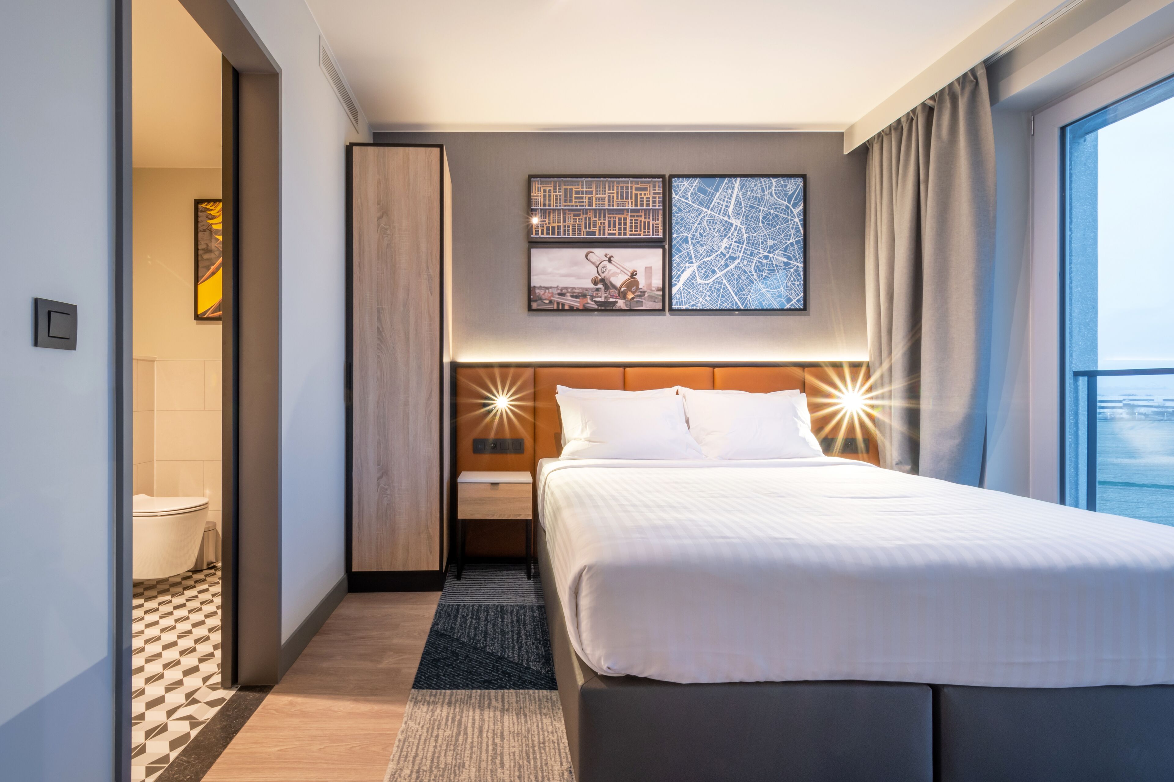 Ein modernes Hotelzimmer mit einem großen Bett, einem Nachttisch, einem Kleiderschrank und Meerblick.