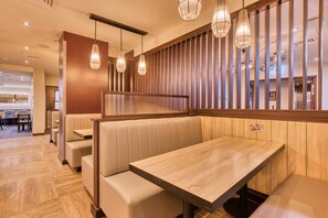 A restaurant with booths, a wooden wall with vertical slats, and pendant lighting. - Premier Inn Dublin Cc Temple Bar (Dublin)
