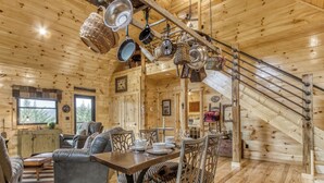 L’intérieur d’un chalet en bois comprend un coin repas, un canapé et un escalier.