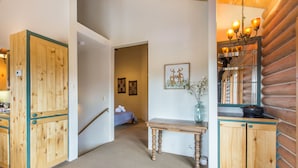 A hallway with wooden walls, a bench, and a table with a vase. - Wrap Around Deck | Unmatched Views | Air Conditioning | STR2025-060 (Ridgway)