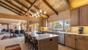 A spacious kitchen with a large island, wooden cabinets, and a view of the outdoors through the windows. - Stunning Views | Spacious | Trail Access | Air Conditioning STR2025-060 (Ridgway)