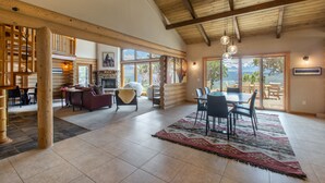 A spacious living area with a fireplace, large windows, and a dining area with a view of the outdoors. - Stunning Views | Spacious | Trail Access | Air Conditioning STR2025-060 (Ridgway)