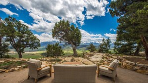 A patio with wicker furniture and a view of mountains and a valley. - Stunning Views | Spacious | Trail Access | Air Conditioning STR2025-060 (Ridgway)