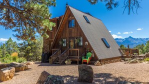 A cabin with a sloped roof, wooden exterior, and a stone foundation.