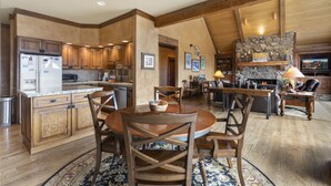 A spacious kitchen with wooden cabinets and a stone fireplace. - Mountain Retreat | Stunning Views | A/C | Hot Tub STR2025-062 (Ridgway)