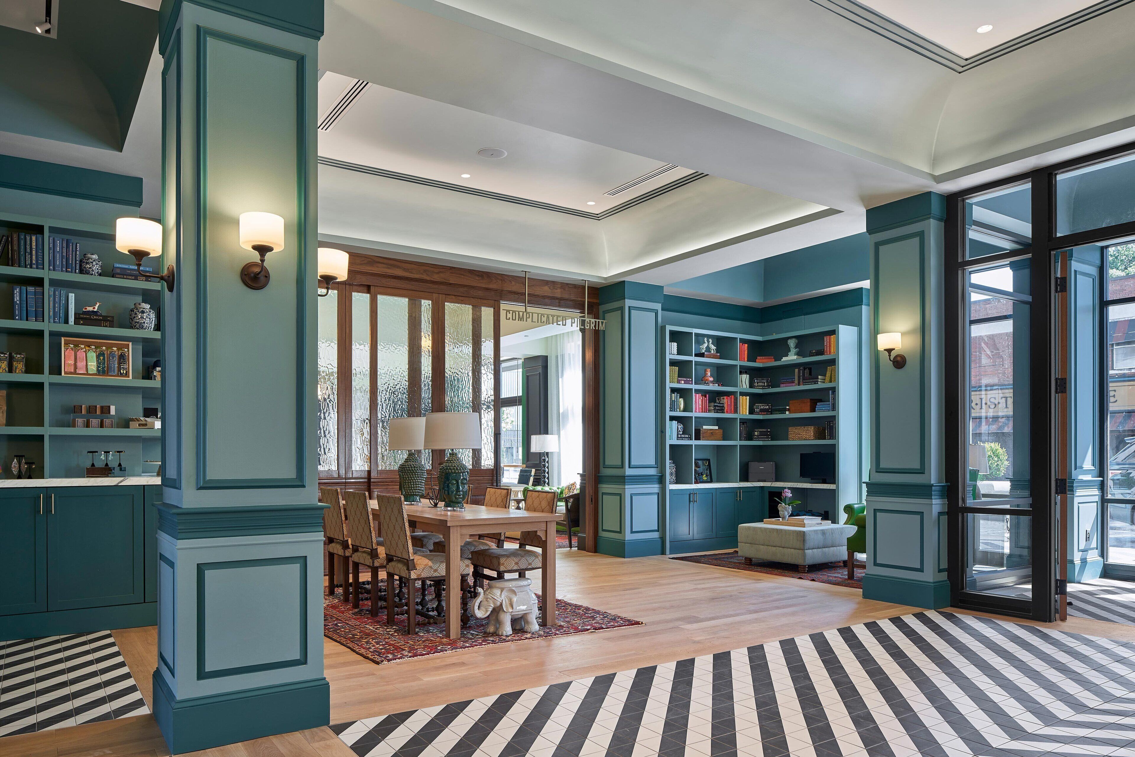 A spacious room with teal cabinetry, a dining area with a wooden table and chairs, and a large window providing natural light.