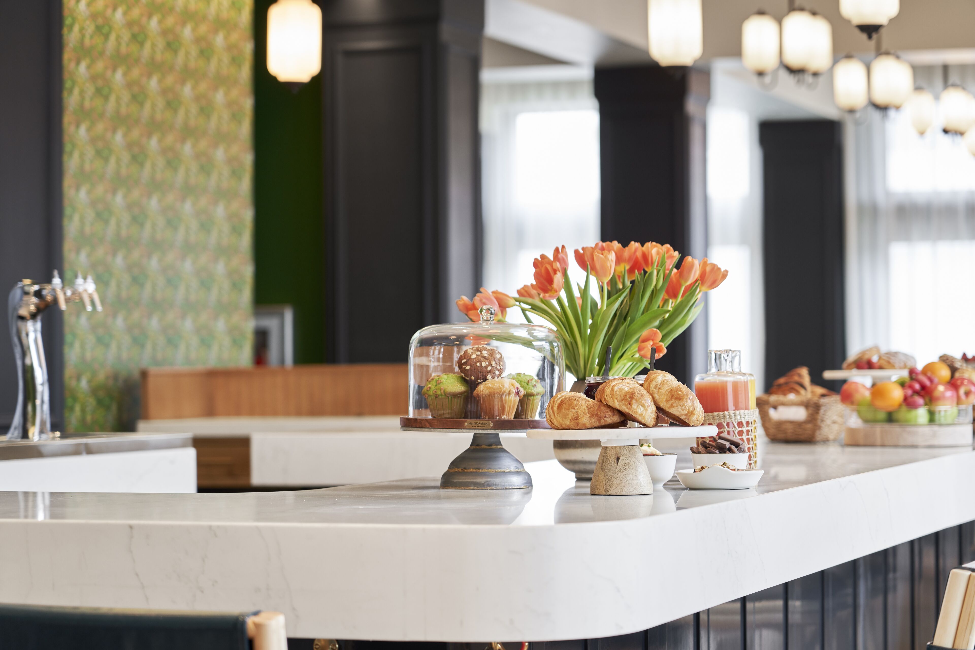 A breakfast buffet with pastries, muffins, and fruit.