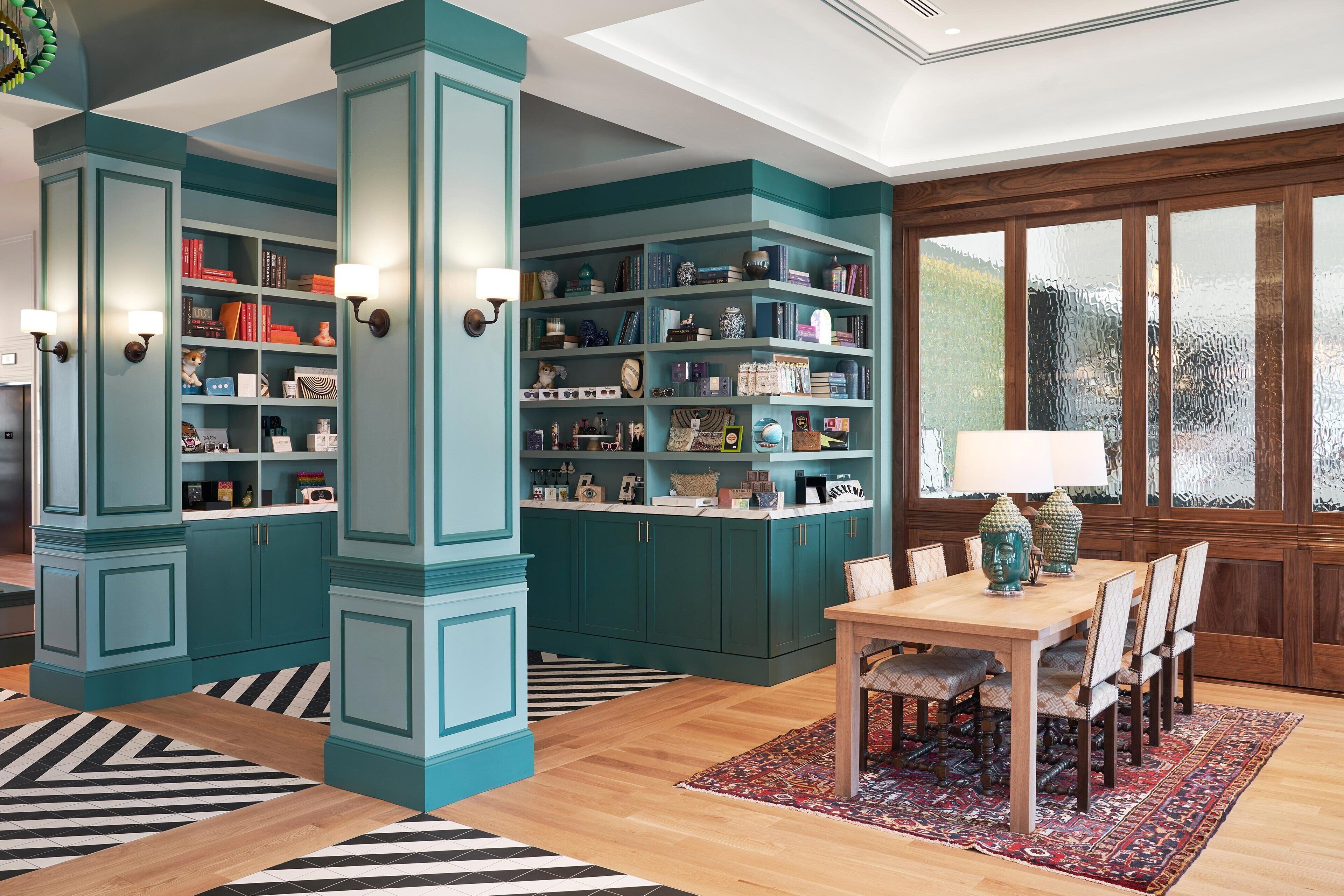 A room with teal cabinetry, a wooden dining table, and a patterned rug.