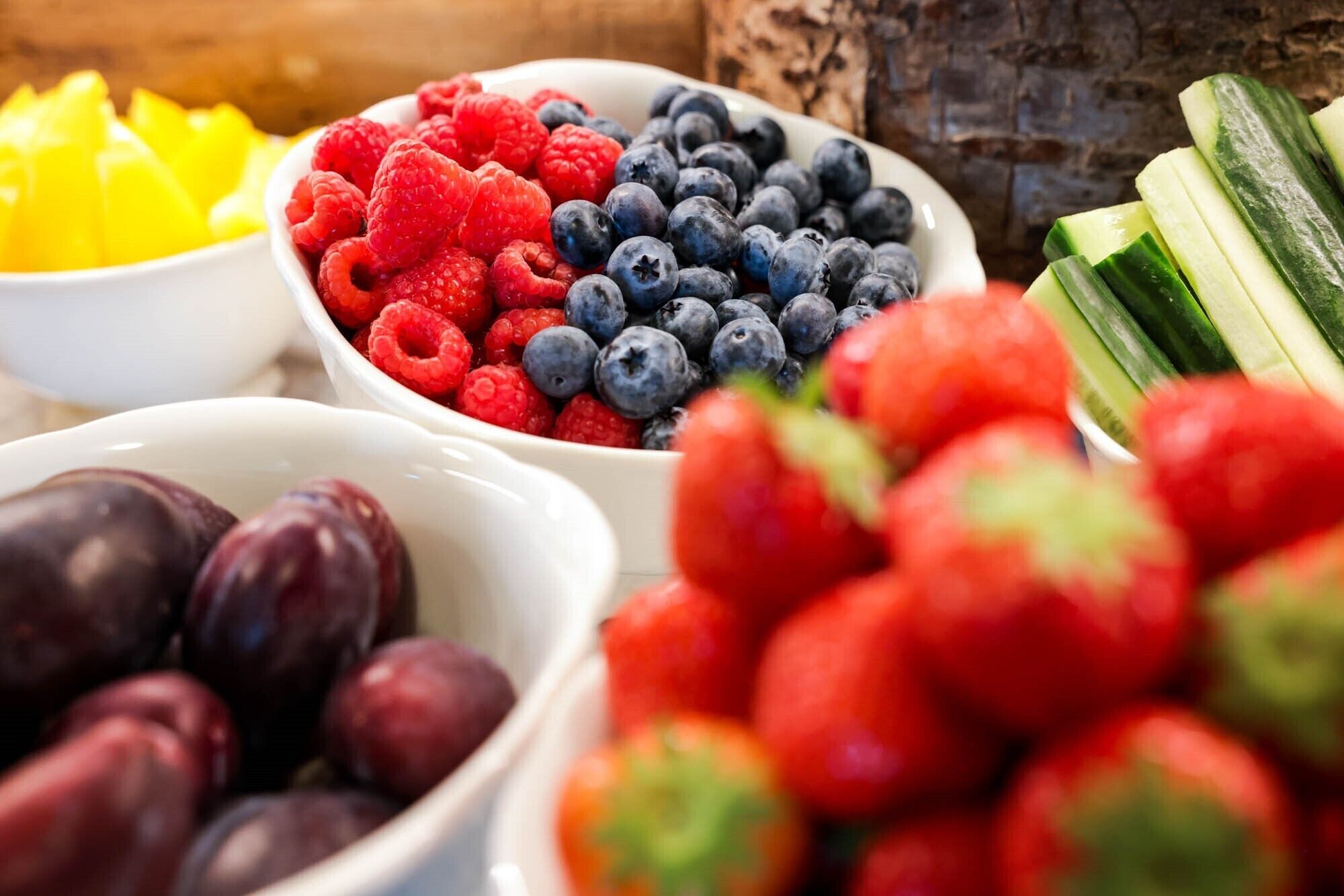 Diversa selección de frutas frescas como frambuesas, arándanos, ciruelas y fresas.