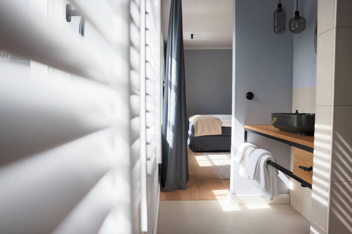 Een moderne slaapkamer met een bed, nachtkastje en een raam met gordijnen.