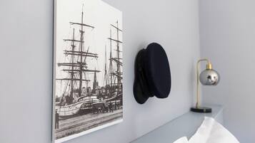 Eine Wand mit einem maritimen Kunstwerk, einem Hut und einer Lampe.