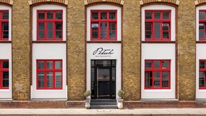 A building with red-framed windows, a central entrance with a sign reading 'Petuh Boutique Hotel,' and a brick facade. - Boutiquehotel Petuh am Hafen - adults only (Flensburg)