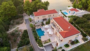 A modern villa with a swimming pool, outdoor seating, and a view of the sea.