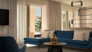 A modern living room with a blue sofa, a round coffee table, and a TV mounted on the wall.