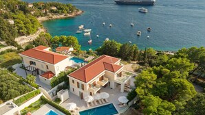 Une propriété située sur la côte, dotée d’une piscine, d’une grande maison et offrant une vue sur la mer et les bateaux.