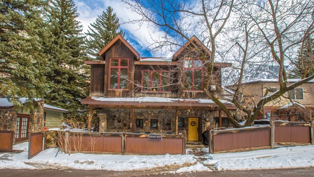 A two-story stone house with a wooden facade, a stone chimney, and a snow-covered roof. - Spacious Getaway | Walk to Downtown | Private Courtyard (Ouray)