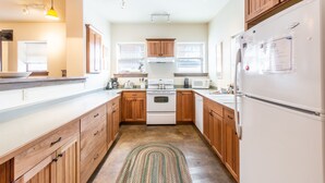 A modern kitchen with wooden cabinets, a white stove, and a refrigerator. - Spacious Getaway | Walk to Downtown | Private Courtyard (Ouray)