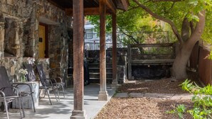 A stone building with a covered patio, outdoor seating, and a tree. - Spacious Getaway | Walk to Downtown | Private Courtyard (Ouray)