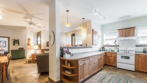 A modern kitchen with wooden cabinets, a built-in oven, and a dining area with a table and chairs. - Spacious Getaway | Walk to Downtown | Private Courtyard (Ouray)