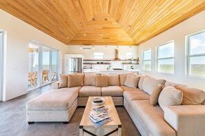 Relax in this spacious living room with a large sofa, coffee table, and kitchen area.