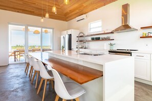 Enjoy cooking in this well-equipped kitchen with a large island, stainless steel appliances, and a spacious window offering a view of the outdoors.
