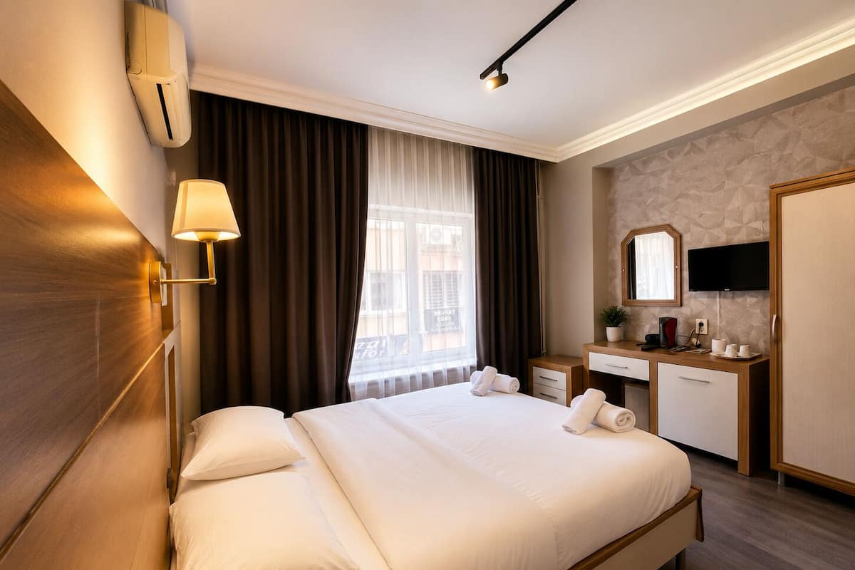 A hotel room with a large bed, bedside lamps, a desk with a mirror, a television, and a window with curtains.