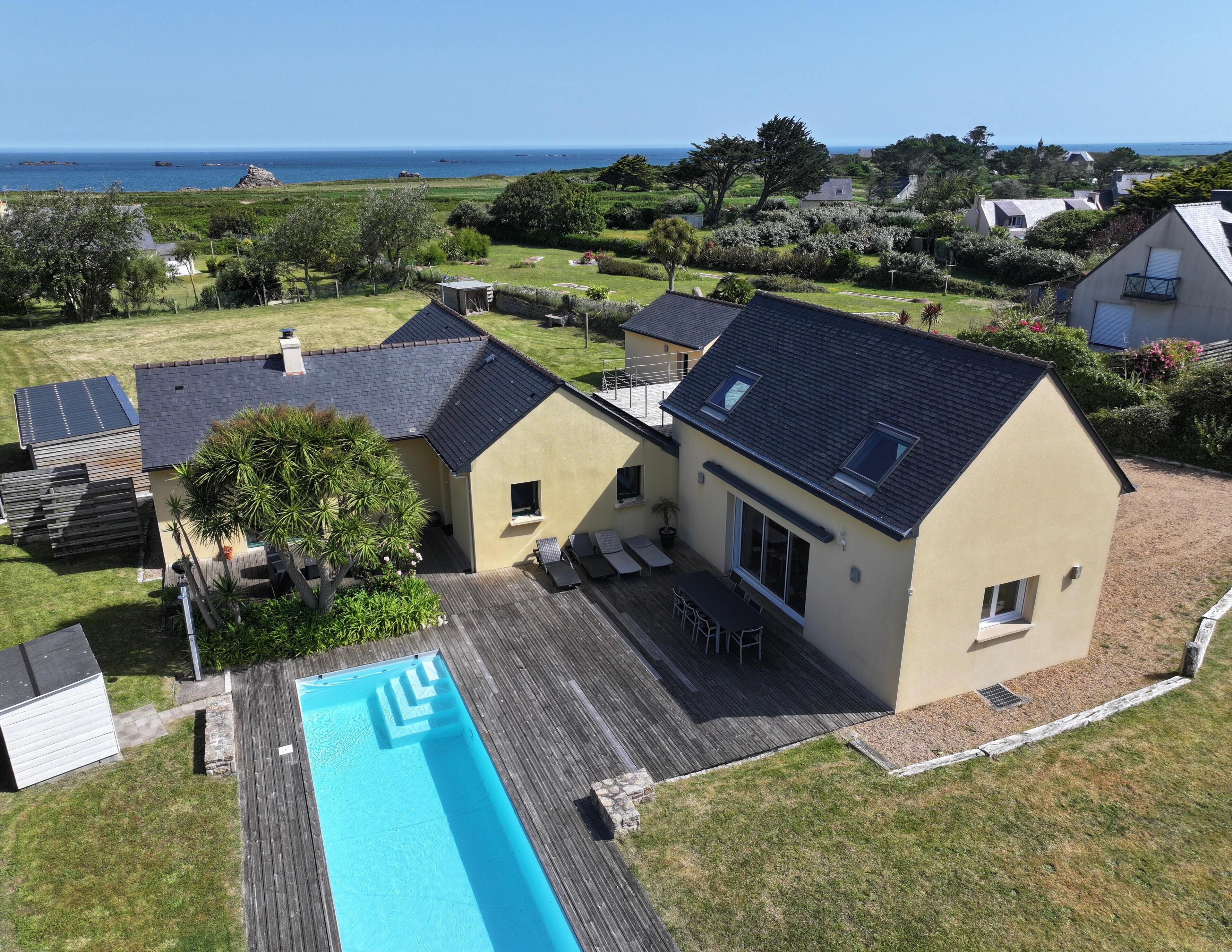 Een huis met twee verdiepingen, een zwembad, een terras en uitzicht op zee.
