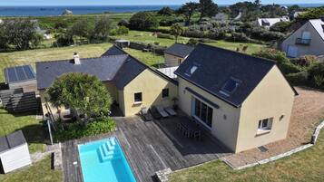 Een huis met twee verdiepingen, een zwembad, een terras en uitzicht op zee.
