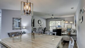 A spacious dining area with a large wooden table, a ceiling fan, and a view of the outdoors through a sliding glass door. - 174 Colonnade Club - Shipyard - 2 Bed 2 Bath Sleeps 5 - Hilton Head Rentals (Hilton Head Island)