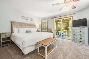 A bedroom with a bed, a wooden bench, a nightstand, a dresser, a television, and a ceiling fan. - Do Duck Inn 4 Bedroom Home in the Heart of Duck (Duck)
