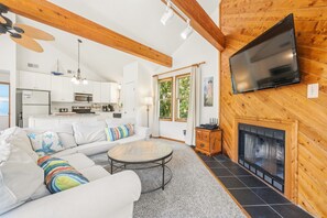 A modern living room with a fireplace, a flat-screen TV mounted on the wall, and a cozy seating area with a sofa and a coffee table. - Do Duck Inn 4 Bedroom Home in the Heart of Duck (Duck)