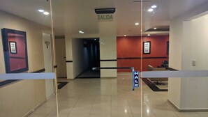 A hotel lobby with a glass partition, a sign reading "SALIDA" (exit), and a "HALE" sign indicating a smoking area. - 3BR La Carolina Quito Parking Sleeps 8 Galapagos Base 700Mbps (Quito)