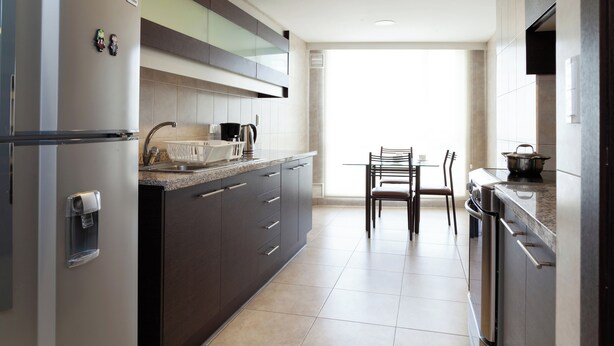 A modern kitchen with a refrigerator, stove, and dining area. - 3BR La Carolina Quito Parking Sleeps 8 Galapagos Base 700Mbps (Quito)