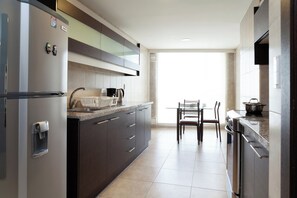 A modern kitchen with a refrigerator, stove, and dining area. - 3BR La Carolina Quito Parking Sleeps 8 Galapagos Base 700Mbps (Quito)