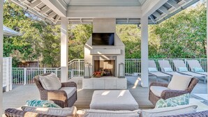 An outdoor patio with wicker furniture, a TV, and a fireplace. - Exquisite Retreat: Enjoy Luxurious Comfort with a Private Pool, Spa, Bikes, and More! (Santa Rosa Beach)