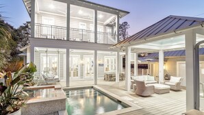 A two-story house with a covered outdoor area featuring a pool and outdoor furniture. - Exquisite Retreat: Enjoy Luxurious Comfort with a Private Pool, Spa, Bikes, and More! (Santa Rosa Beach)