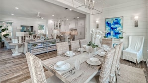 A spacious dining area with a large wooden table set for six, surrounded by wicker chairs. - Exquisite Retreat: Enjoy Luxurious Comfort with a Private Pool, Spa, Bikes, and More! (Santa Rosa Beach)