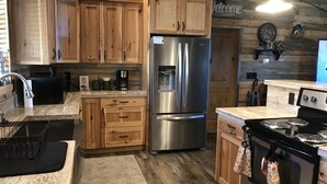 Una cocina con armarios de madera, un refrigerador de acero inoxidable, una estufa y una cafetera.