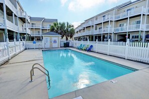 A pool area with a clear blue pool, white fences, and multiple balconies on the buildings. - Unobstructed Ocean Views!  4 Bedroom townhouse, beach access, community pool (Surf City)