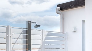 A white outdoor shower with a metal frame and a wooden platform. - Vista sulle Cupole by Wonderful Italy (Palermo)