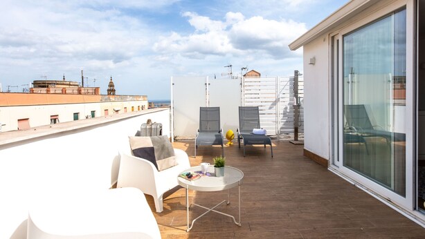 A rooftop terrace with a white sofa, two chairs, a small round table, and a potted plant. - Vista sulle Cupole by Wonderful Italy (Palermo)