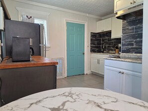 A kitchen with a refrigerator, a coffee maker, a sink with a black backsplash, and a blue door. - Wesher Studio H By Downtown, Walk to GWCC & Mercedes Benz Stadium (Atlanta)