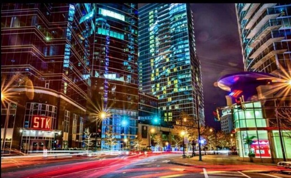 A nighttime cityscape with illuminated high-rise buildings and a prominent STK sign.