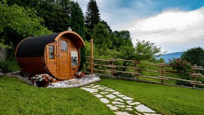 Una cabaña de madera con techo curvo, una puerta de madera y un pequeño porche con plantas en macetas.