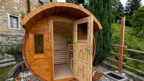 Una sauna de madera con techo curvo, puertas abiertas y una pequeña ventana.